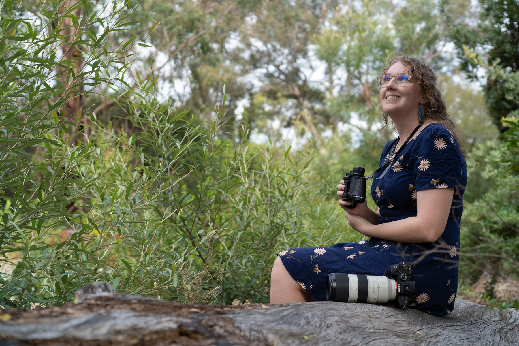 Olivia Congdon sitting on a log in the wilderness.
