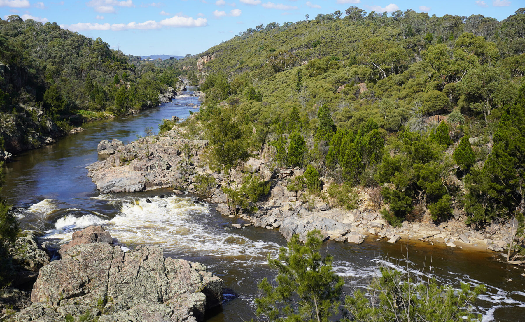 An aerial view of Red Rock Gorge with trees growing on rocky terrain and a lake.