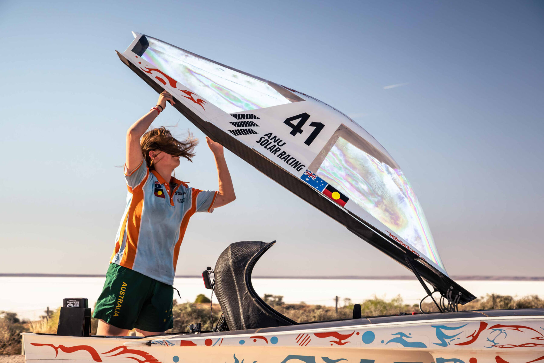 Lucy Legge adjusts the canopy at a quick photo stop for ANU Solar Racing at Lake Hart, SA.