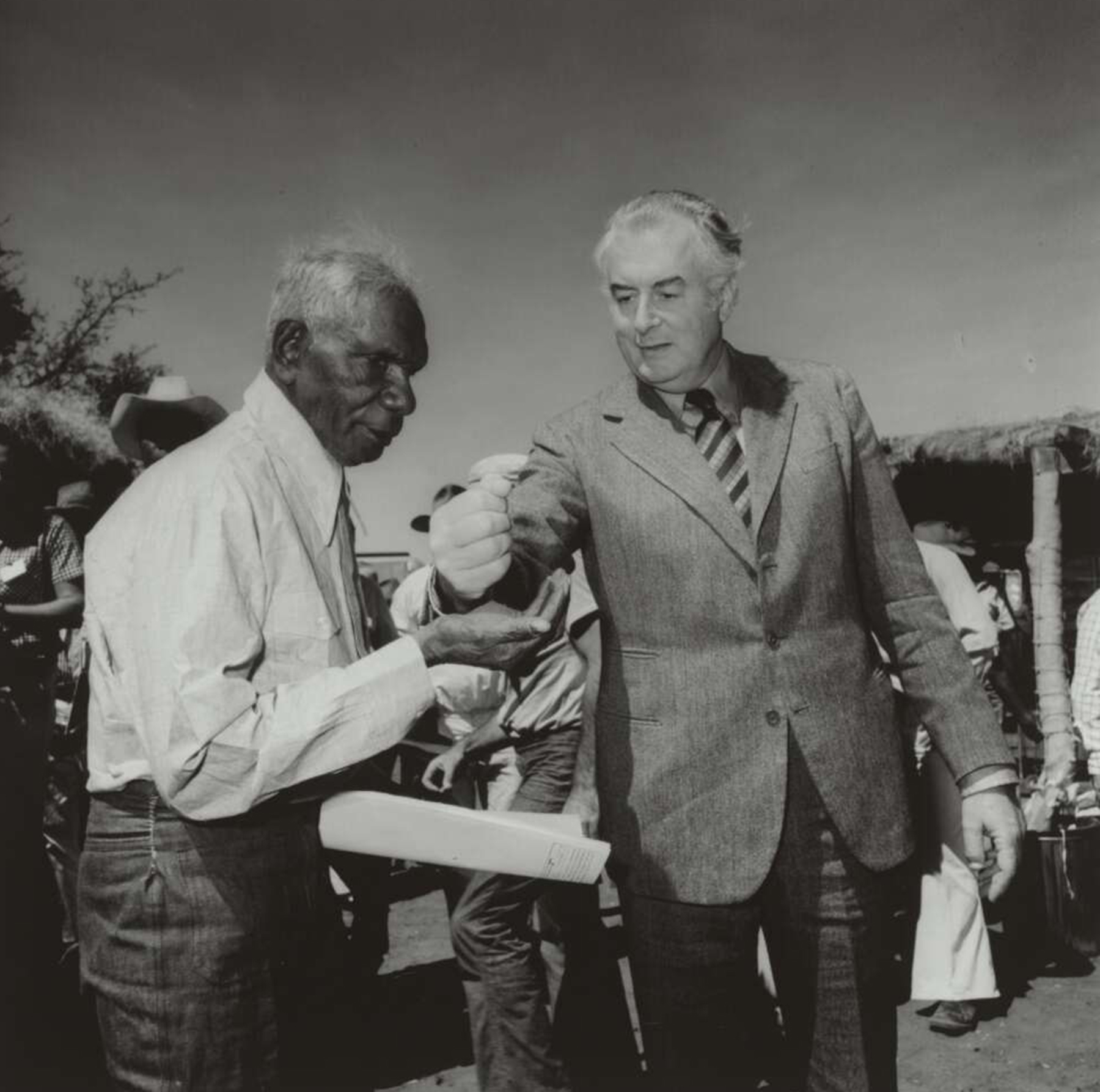 Prime minister Gough Whitlam pours soil into the hand of Gurindji Traditional Land Owner Vincent Lingiari at Wattie Creek, Northern Territory, 16 August 1975.