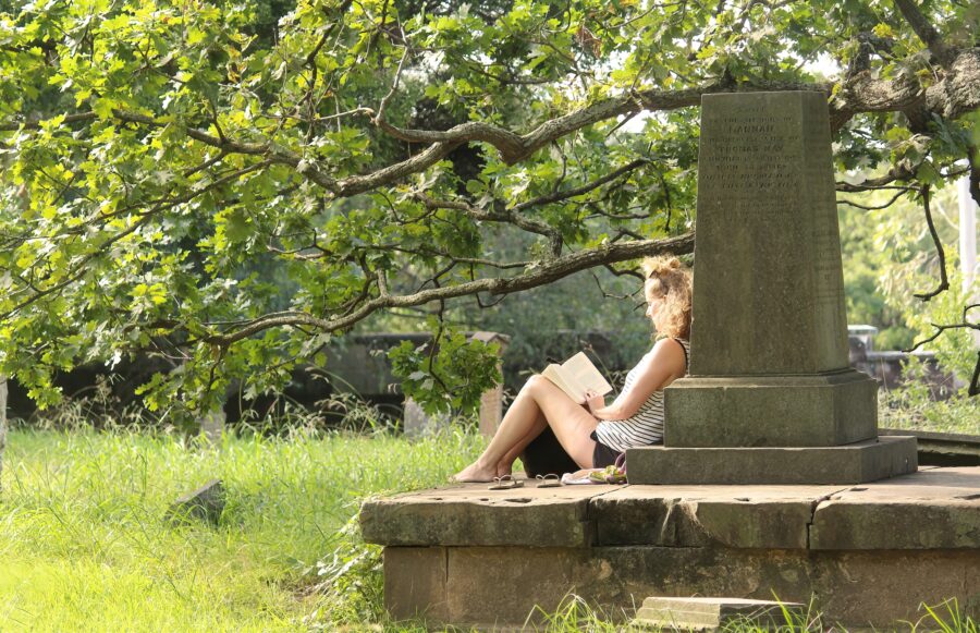 A woman reading a book on a gravetstone at Camperdown Cemetery in Newtown, Sydney.