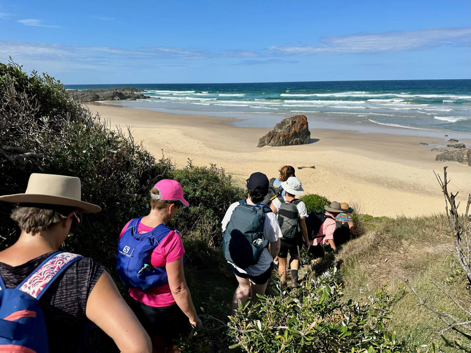 Hikers coming down a incline onto a beach