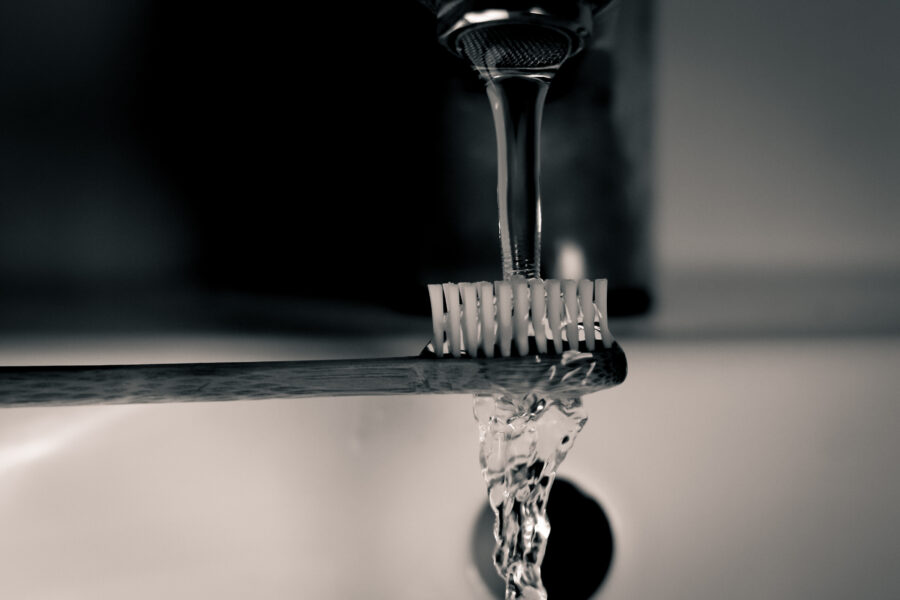 A toothbrush under a running tap.