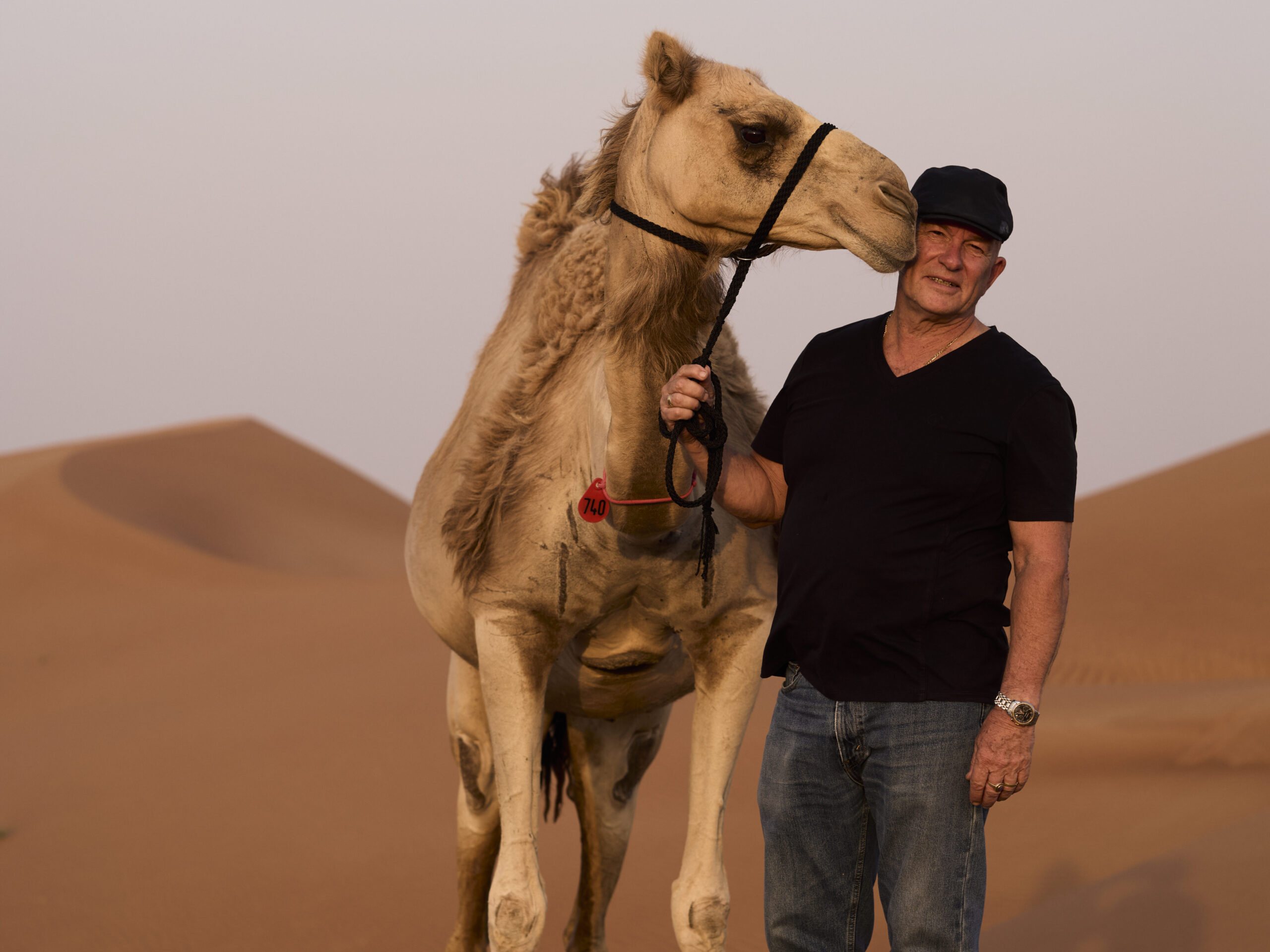 Dr Alex Tinson with a camel on red sand dunes