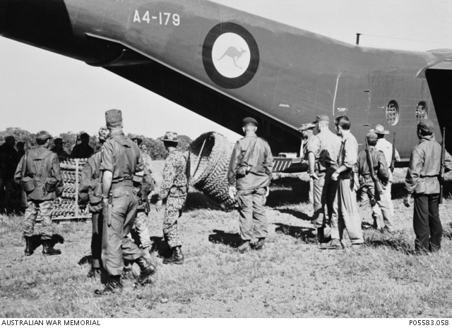A group of Special Forces soldiers watch as barbed wire is unloaded from the cargo compartment of A4-179, a Caribou of the RAAF Transport Flight Vietnam (RTFV).
