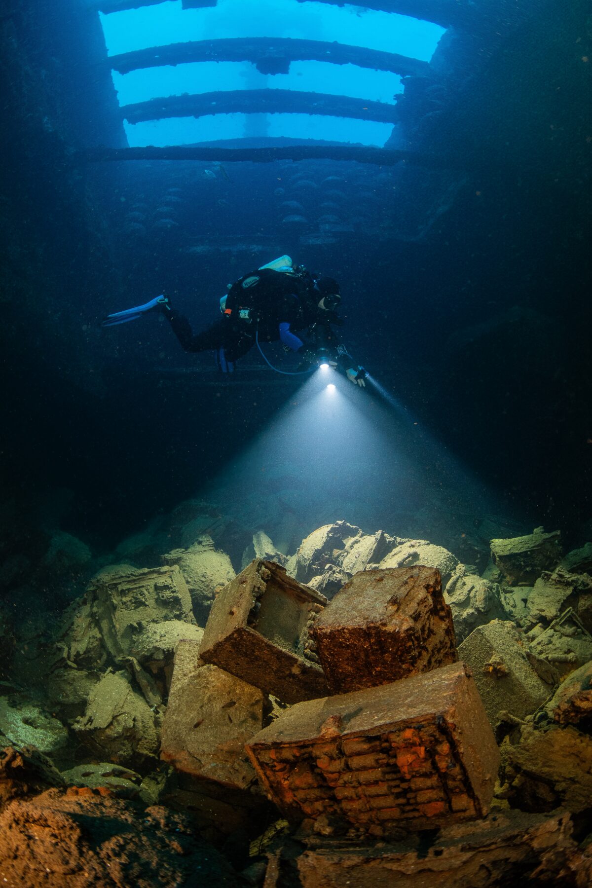 A diver examines the rusting munitions stored inside the cargo hold of the San Francisco Maru shipwreck