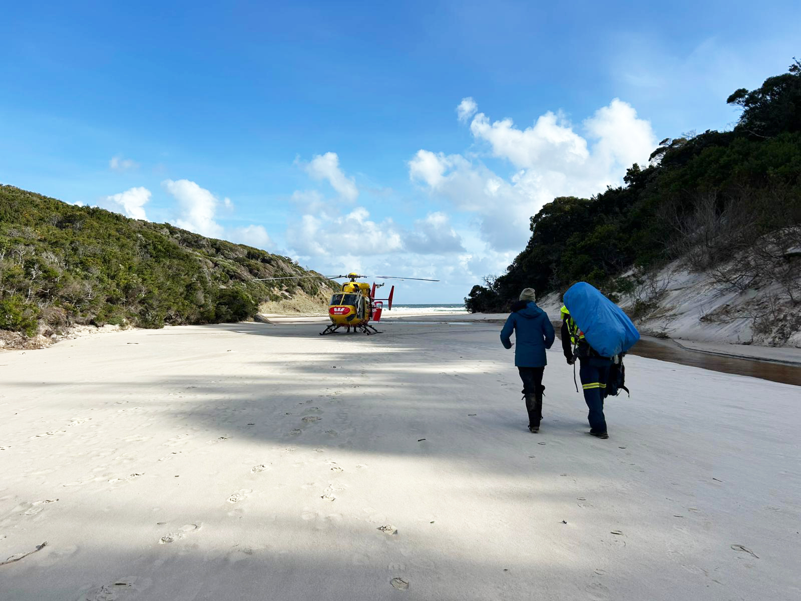 Rob and Anna walk across beach to waiting a rescue helicopter